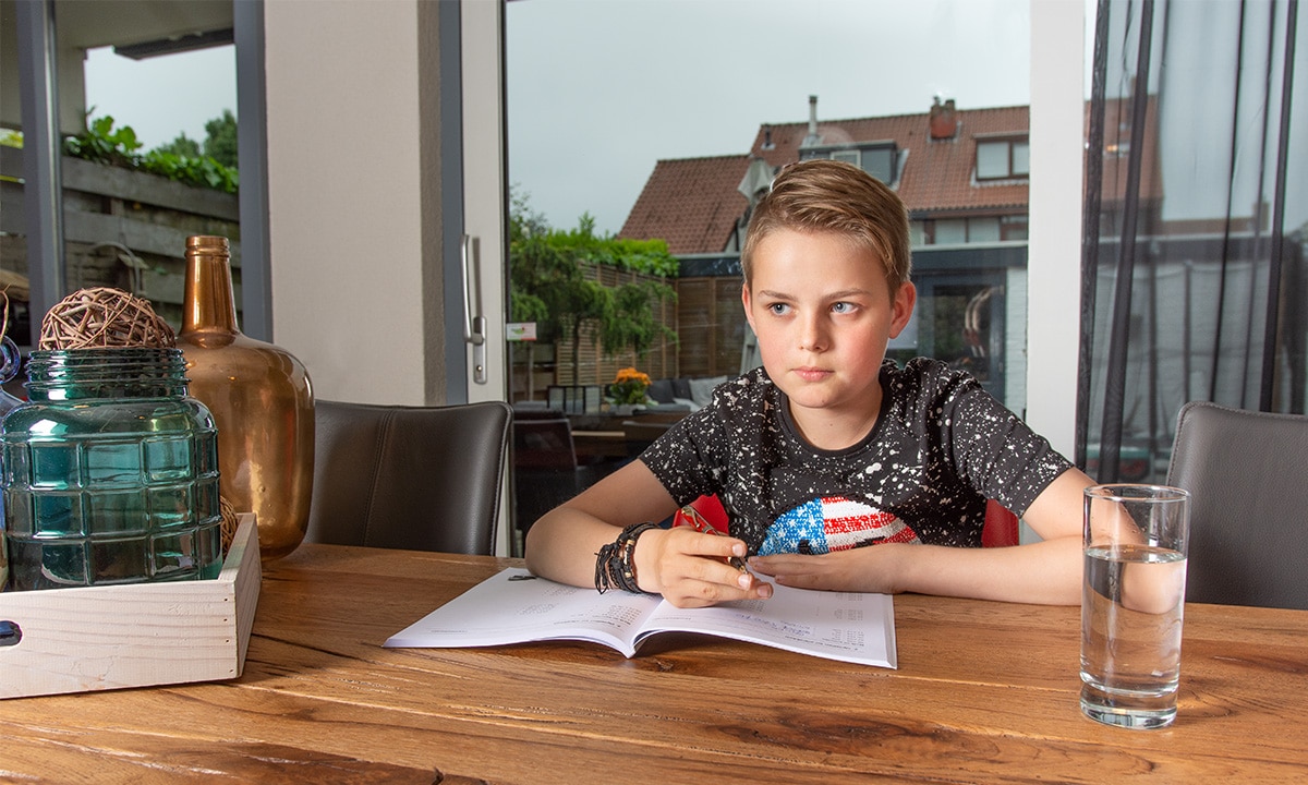 jongen aan tafel met werkboek