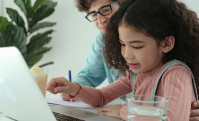 Vader en dochter zitten samen achter een laptop huiswerk te maken